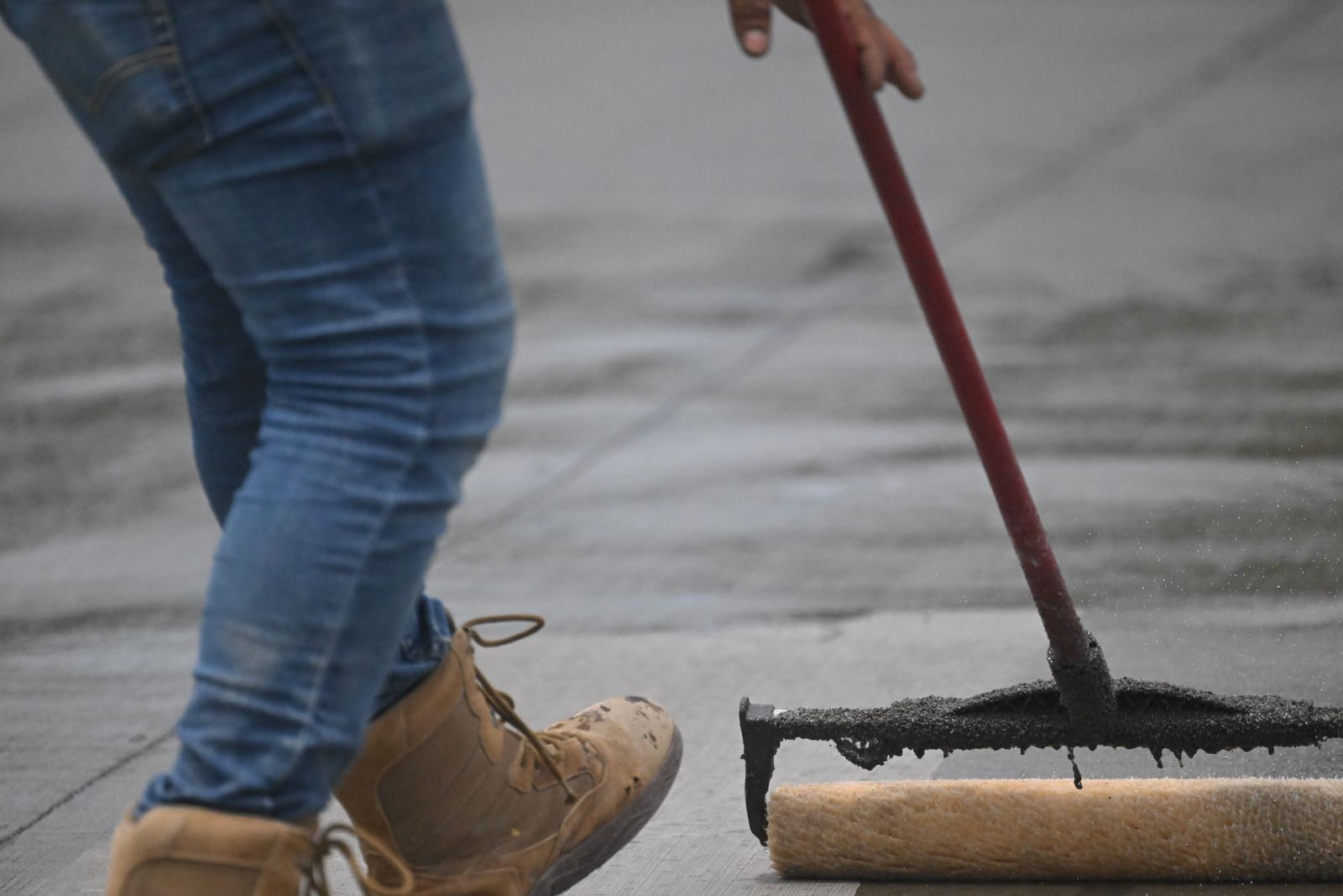 Worker rolling sealer onto a concrete floor